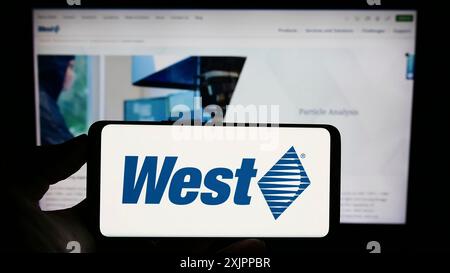 Stuttgart, Allemagne, 08-12-2013 2023 : personne tenant un téléphone portable avec le logo de la société américaine West Pharmaceutical services Inc sur l'écran devant Banque D'Images