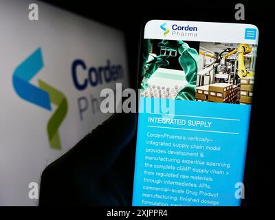 Stuttgart, Allemagne, 11-07-2023 : personne tenant un smartphone avec le site de la société pharmaceutique CDMO CordenPharma devant le logo de l'entreprise. Mise au point Banque D'Images