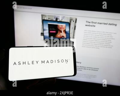 Stuttgart, Allemagne, 08-18-2023 : personne tenant un téléphone portable avec le logo de la société de rencontres en ligne The Ashley Madison Agency sur l'écran en face de la page web. Banque D'Images