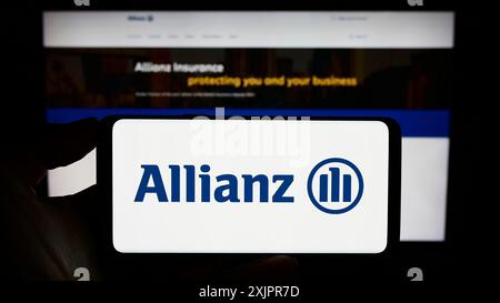 Stuttgart, Allemagne, 08-20-08 2023 : personne tenant un smartphone avec le logo de la compagnie d'assurance allemande Allianz se sur l'écran devant le site. Concentrez-vous sur Banque D'Images