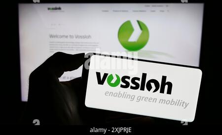 Stuttgart, Allemagne, 08-24-2023 : personne tenant un téléphone portable avec le logo de la société allemande de technologie ferroviaire Vossloh AG sur l'écran devant l'entreprise Banque D'Images