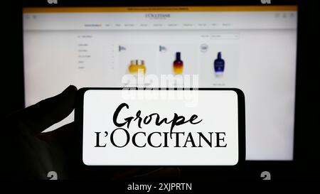 Stuttgart, Allemagne, 08 30 2023 : personne tenant un téléphone portable avec le logo de la société française de cosmétiques Groupe L'Occitane sur l'écran devant l'entreprise Banque D'Images