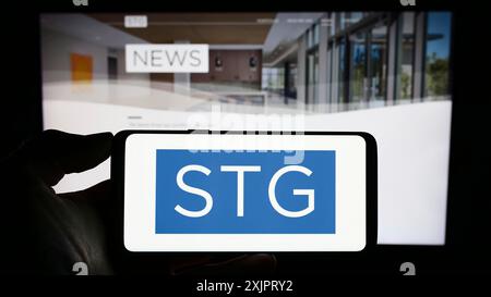 Stuttgart, Allemagne, 08 28 2023 : personne tenant un téléphone portable avec le logo de la société américaine de capital-investissement STG Partners LLC sur l'écran devant l'entreprise Banque D'Images