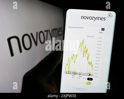 Stuttgart, Allemagne, 09-17-2023 : personne tenant un téléphone portable avec la page web de la société danoise de biotechnologie Novozymes COMME sur l'écran devant le logo. Mise au point Banque D'Images