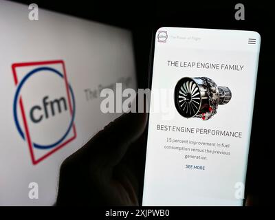 Stuttgart, Allemagne, 09-22-2023 : personne tenant un téléphone portable avec la page Web de la compagnie de moteurs d'avion CFM International sur l'écran devant le logo. Mise au point Banque D'Images