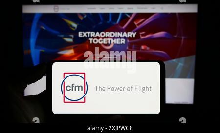 Stuttgart, Allemagne, 09-22-2023 : personne tenant un smartphone avec le logo de la société de moteurs d'avion CFM International sur l'écran en face du site Web. Mise au point Banque D'Images