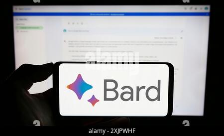 Stuttgart, Allemagne, 09-23-2023 : personne tenant un téléphone portable avec le logo du chatbot génératif ai Google Bard sur l'écran en face de la page Web de l'entreprise. Mise au point Banque D'Images