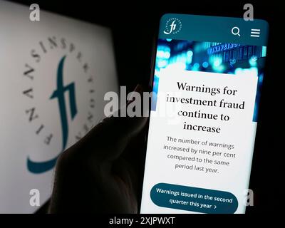 Stuttgart, Allemagne, 09-24-2023 : personne tenant un smartphone avec la page web du régulateur financier suédois Finansinspektionen sur l'écran avec le logo. Mise au point Banque D'Images