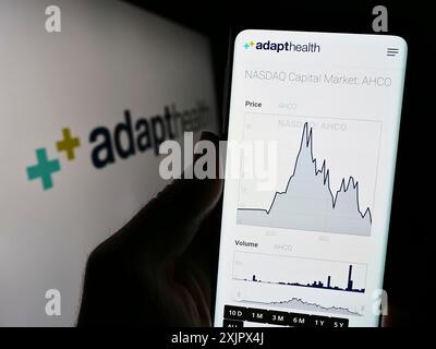 Stuttgart, Allemagne, 09 25 2023 : personne tenant un téléphone portable avec la page Web de la société américaine de soins de santé AdaptHealth LLC devant le logo de l'entreprise. Concentrez-vous sur Banque D'Images