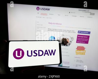 Stuttgart, Allemagne, 09-27-2023, personne tenant un smartphone avec le logo de l'Union of Shop distributive and Allied Workers (USDAW) devant le site. Banque D'Images