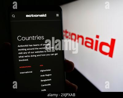 Stuttgart, Allemagne, 10-08-2023 : personne tenant un smartphone avec la page web de l'organisation caritative internationale ActionAid devant le logo. Concentrez-vous sur Banque D'Images