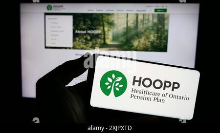 Stuttgart, Allemagne, 10-16-2023 : personne tenant un téléphone intelligent avec le logo de Healthcare of Ontario pension Plan (HOOPP) devant le site Web. Concentrez-vous sur le téléphone Banque D'Images