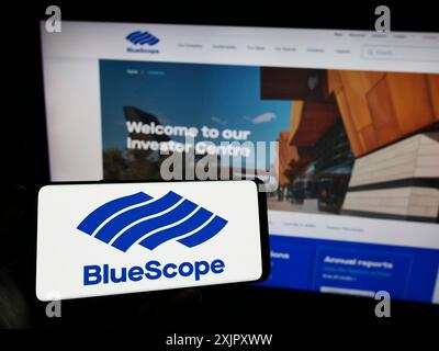 Stuttgart, Allemagne, 10-16-2023 : personne tenant un téléphone portable avec le logo de la société australienne BlueScope Steel Limited en face de la page Web de l'entreprise. Mise au point Banque D'Images