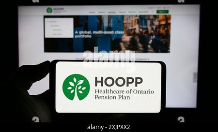 Stuttgart, Allemagne, 10-16-2023 : personne tenant un téléphone cellulaire avec le logo de Healthcare of Ontario pension Plan (HOOPP) devant la page Web de l'entreprise. Mise au point Banque D'Images