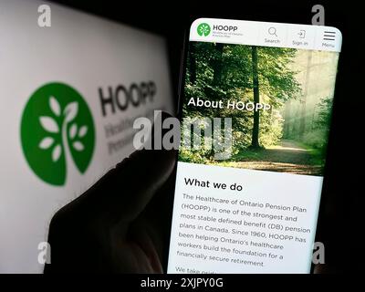 Stuttgart, Allemagne, 10-16-2023 : personne tenant un téléphone intelligent avec le site Web de Healthcare of Ontario pension Plan (HOOPP) devant le logo de l'entreprise. Mise au point Banque D'Images