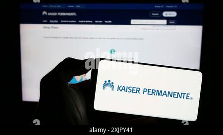 Stuttgart, Allemagne, 10 27 2023 : personne tenant un téléphone portable avec le logo du consortium américain de soins gérés Kaiser permanente devant la page Web de l'entreprise. Banque D'Images