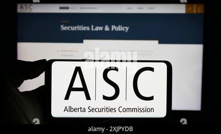 Stuttgart, Allemagne, 10 29 2023 : personne tenant un téléphone cellulaire avec le logo de l'organisme de réglementation Alberta Securities Commission (ASC) devant la page Web. Banque D'Images