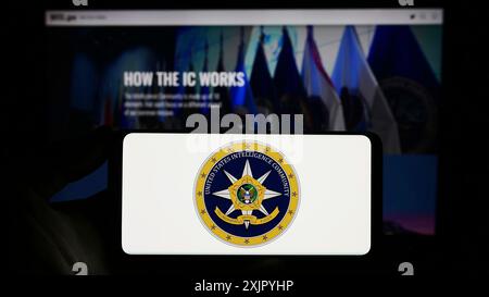 Stuttgart, Allemagne, 10 29 2023 : personne tenant un smartphone avec le sceau du groupe d'agences United States Intelligence Community (IC) devant le site Web. Banque D'Images