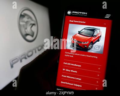 Stuttgart, Allemagne, 10 31 2023 : personne tenant un téléphone portable avec la page Web de la société automobile malaisienne Proton Holdings Berhad (PHB) avec le logo. Mise au point Banque D'Images