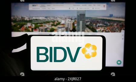 Stuttgart, Allemagne, 11-03-2023 : personne tenant un smartphone avec le logo de la Banque commerciale pour l'investissement et le développement du Vietnam en face du site. Banque D'Images