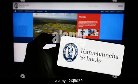 Stuttgart, Allemagne, 11-03-2023 : personne tenant un téléphone portable avec le logo de l'organisation d'éducation privée hawaïenne Kamehameha Schools devant la page web. Banque D'Images