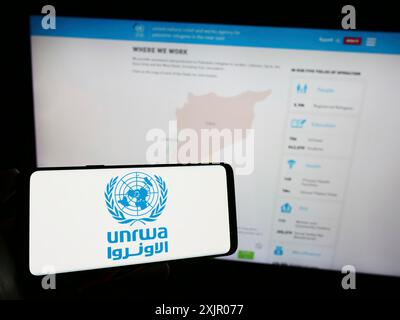 Stuttgart, Allemagne, 11-03-2023 : personne tenant un téléphone portable avec le logo de l'agence des Nations Unies Plalestine pour les réfugiés UNRWA devant la page Web. Concentrez-vous sur Banque D'Images