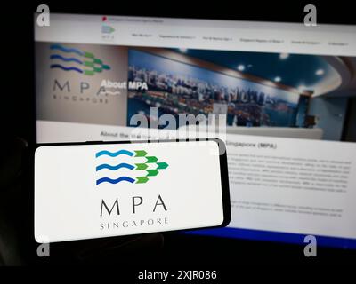 Stuttgart, Allemagne, 11-06-2023 : personne tenant un smartphone avec le logo de l'Autorité maritime et portuaire de Singapour (MPA) devant le site. Concentrez-vous sur Banque D'Images