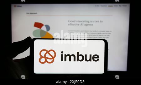 Stuttgart, Allemagne, 11-07-2023 : personne tenant un smartphone avec le logo de la société de recherche américaine en intelligence artificielle (IA) imbue devant le site Web. Banque D'Images