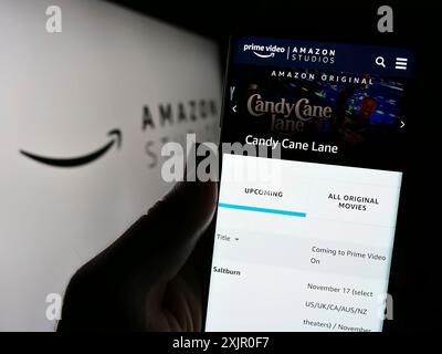 Stuttgart, Allemagne, 11-08-2023 : personne tenant un smartphone avec la page web de la société américaine de production cinématographique et télévisuelle Amazon Studios avec le logo. Mise au point Banque D'Images