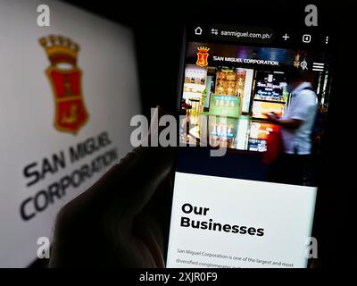 Stuttgart, Allemagne, 11-08-2023 : personne tenant un téléphone portable avec la page web de la société philippine San Miguel Corporation (SMC) devant le logo. Concentrez-vous sur Banque D'Images