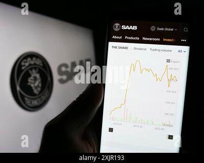 Stuttgart, Allemagne, 11-16-2023 : personne tenant un smartphone avec le site Web de la société suédoise de l'aérospatiale et de la défense Saab AB devant le logo. Concentrez-vous sur Banque D'Images