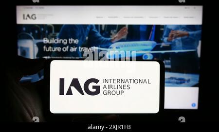 Stuttgart, Allemagne, 11-17-2023 : personne tenant un smartphone avec le logo d'International Consolidated Airlines Group S.A. (IAG) devant le site. Banque D'Images