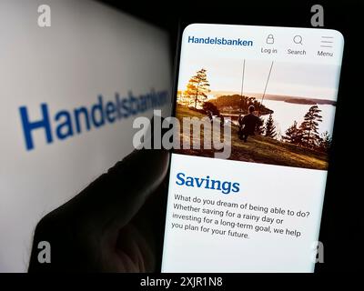 Stuttgart, Allemagne, 11-22-2023 : personne tenant un smartphone avec le site web de la société financière suédoise Svenska Handelsbanken AB devant le logo. Mise au point Banque D'Images