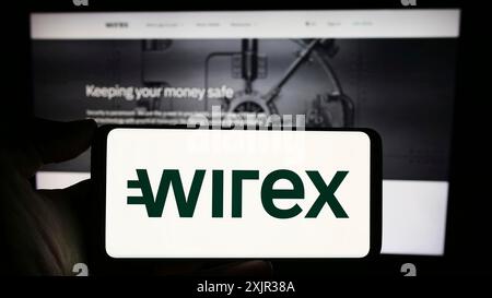 Stuttgart, Allemagne, 12-18-2023 : personne tenant un téléphone portable avec le logo de la société fintech croate Wirex Digital d.o.o devant la page web de l'entreprise. Banque D'Images