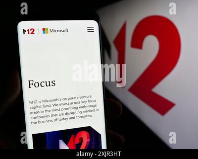 Stuttgart, Allemagne, 12-20-2023 : personne tenant un téléphone portable avec la page Web de la société américaine de capital-risque M12 (Microsoft) devant le logo de l'entreprise. Mise au point Banque D'Images