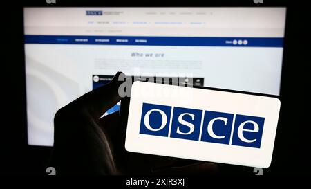 Stuttgart, Allemagne, 12-28-2023. Personne tenant un smartphone avec le logo de l'Organisation pour la sécurité et la coopération en Europe (OSCE) devant Banque D'Images