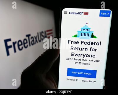 Stuttgart, Allemagne, 12 28 2023 : personne tenant un téléphone portable avec la page Web de la société américaine de logiciels fiscaux en ligne FreeTaxUSA devant le logo de l'entreprise. Mise au point Banque D'Images