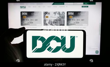 Stuttgart, Allemagne, 02-06-2024 : personne tenant un téléphone portable avec le logo de l'institution financière Digital Federal Credit Union (DCU) devant la page Web. Banque D'Images