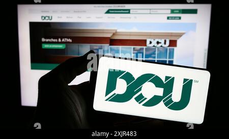 Stuttgart, Allemagne, 02-06-2024 : personne tenant un smartphone avec le logo de l'institution financière Digital Federal Credit Union (DCU) devant le site Web. Banque D'Images