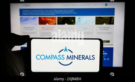 Stuttgart, Allemagne, 02-08-2024 : personne tenant un smartphone avec le logo de la société minière américaine Compass Minerals International Inc en face du site Web. Banque D'Images