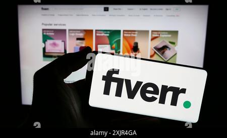 Stuttgart, Allemagne, 02-11-2024 : personne tenant un smartphone avec le logo de la société de plate-forme freelance Fiverr International Ltd en face du site Web. Banque D'Images