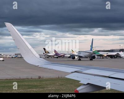 Avions au terminal 2 de l'aéroport de Londres Heathrow par temps nuageux Banque D'Images