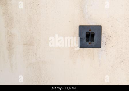 Ancien interrupteur en plastique gris sur le mur abandonné beige Banque D'Images