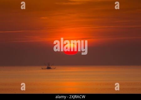 Bateau de pêche solitaire avec chalut dans la mer du Nord au coucher du soleil, Buesum, Schleswig-Holstein, Allemagne Banque D'Images