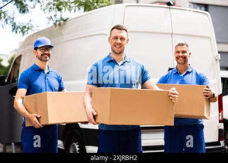 Déménageurs professionnels chargeant une fourgonnette avec des boîtes pour un déménagement, chauffeur de camion efficace exécutant des services de déménagement avec l'équipe. Banque D'Images