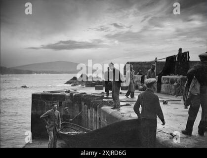 Vingt ans avant que les îles Blasket au large de la péninsule de Dingle, dans le comté de Kerry en Irlande, soient évacuées en 1954, les insulaires débarquent d'une carrosse. Great Blasket peut être vu au loin dans la photographie d'Ellen O'Connor (1874-1943). Banque D'Images