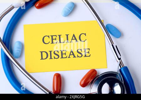 Concept de maladie cœliaque sans gluten. Mots MALADIE CŒLIAQUE sur une carte de visite jaune dans une composition avec un stéthoscope et des pilules Banque D'Images