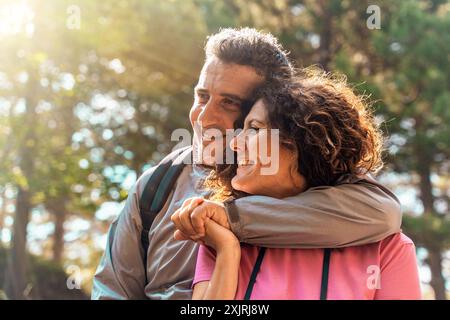 Joyeux couple d'âge moyen embrassant dans un cadre naturel. L'homme et la femme sourient chaleureusement, montrant l'amour et la compagnie. Filtres de lumière solaire th Banque D'Images