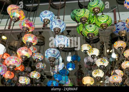 Une variété de lampes en mosaïque colorées suspendues au plafond dans un marché. Lumineux et dynamique dans un contexte de marché. Concept d'éclairage traditionnel Banque D'Images