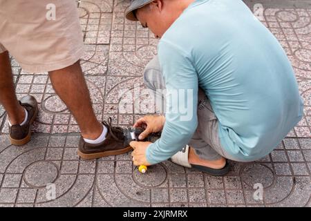 Ho Chi Minh ville, Vietnam - 20 mai 2024 : un cireur de chaussures de rue au travail. Banque D'Images